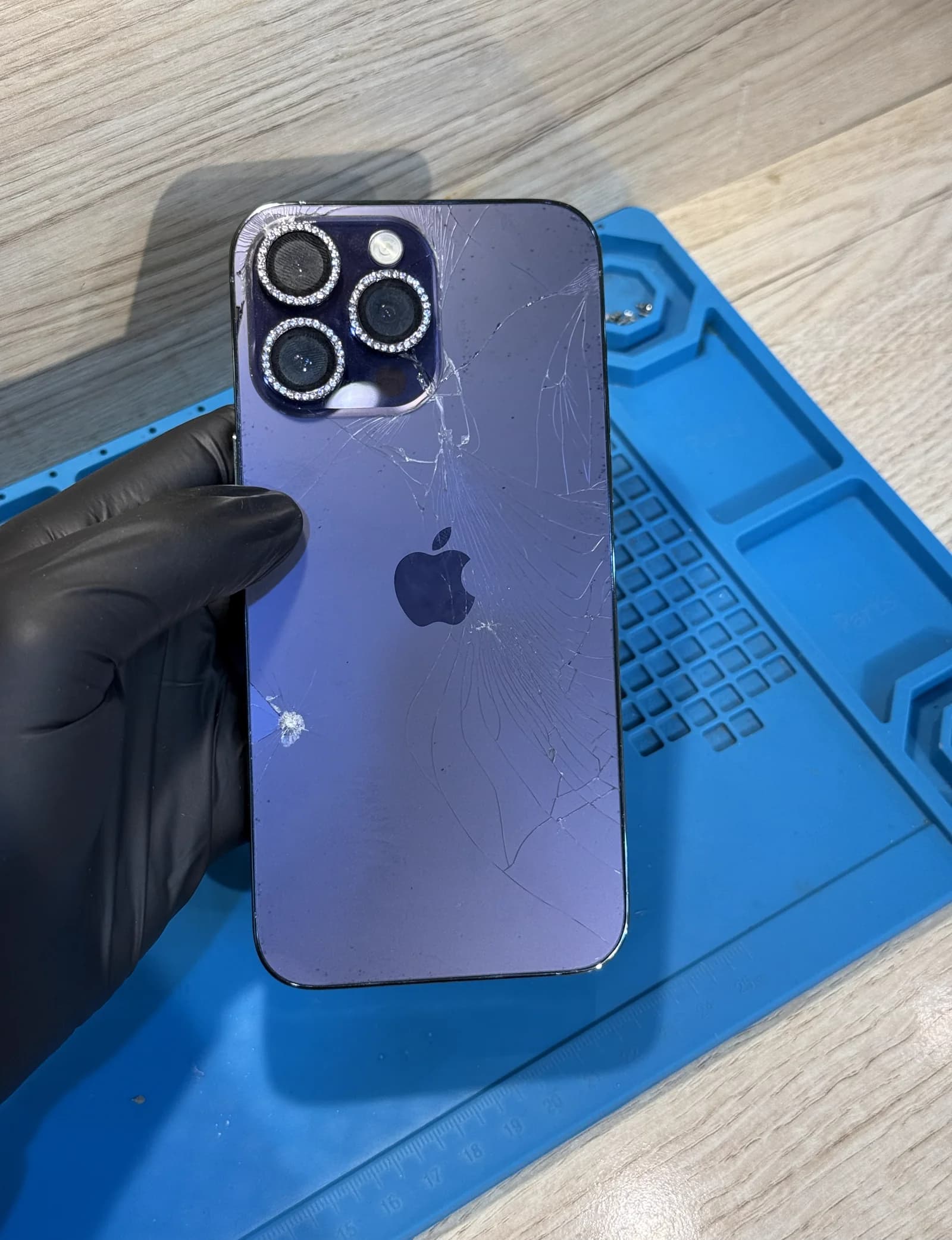 Purple iPhone with badly cracked back glass before repair